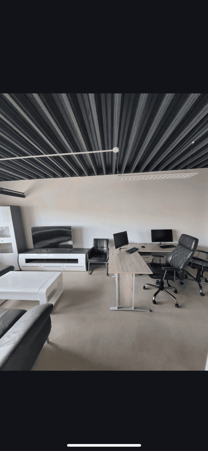 Modernes Büro mit Schreibtisch, Computern, bequemer Sitzecke und einer auffälligen Deckenverkleidung.