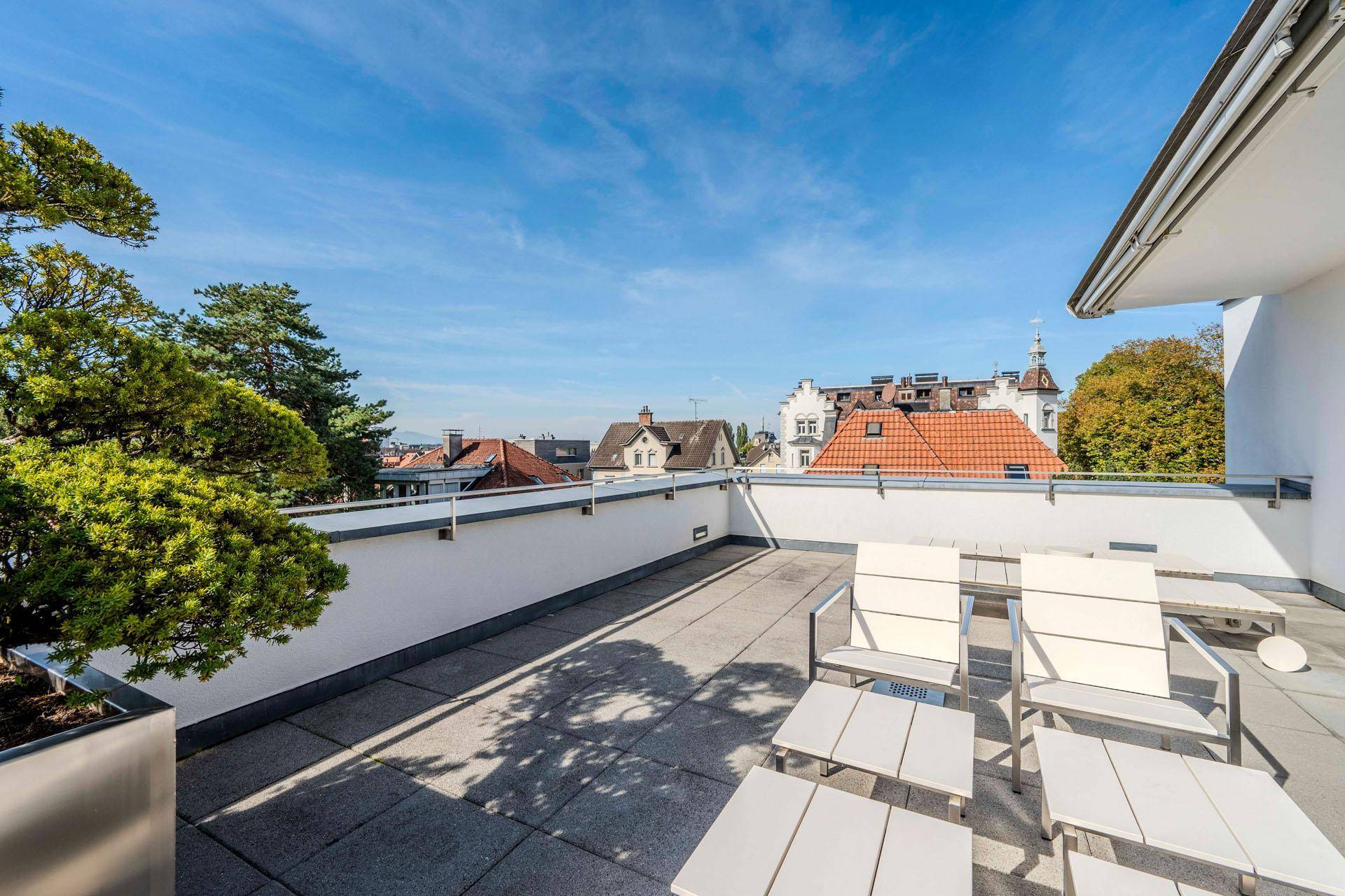 Geräumige Dachterrasse mit Sitzgelegenheiten und weitem Blick über die Stadt und Dächer.