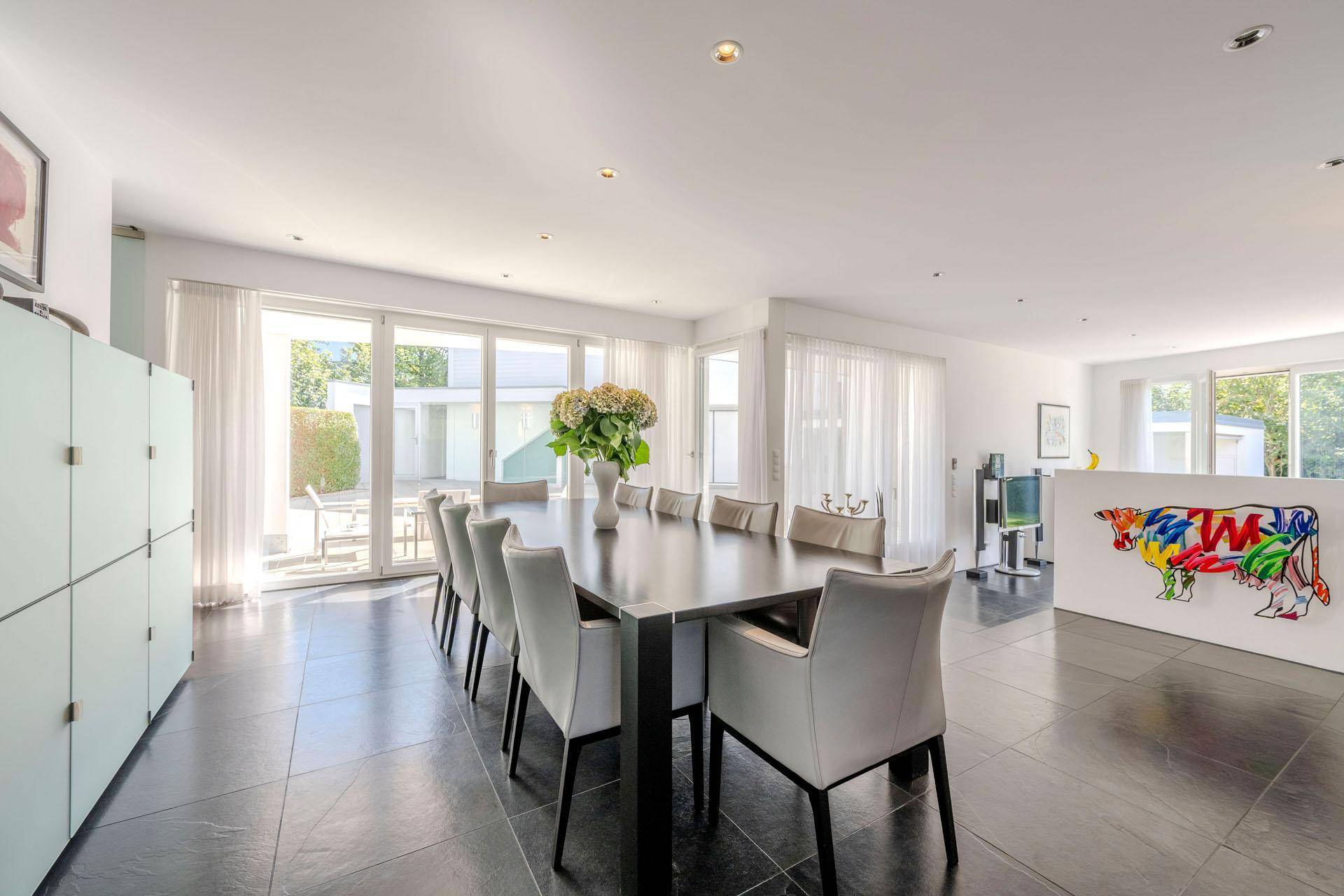 Heller Essbereich mit großem Esstisch, modernen Stühlen und Zugang zur Terrasse.