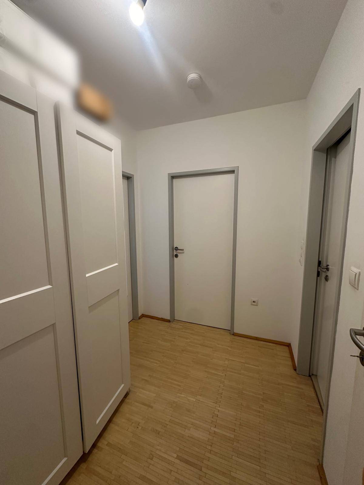 Heller Flur mit Holzboden und weißen Türen, bietet Zugang zu verschiedenen Räumen.
