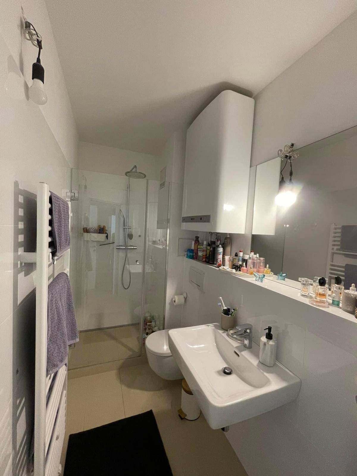 Modernes Badezimmer mit begehbarer Dusche, Einzelwaschbecken und beheiztem Handtuchhalter.