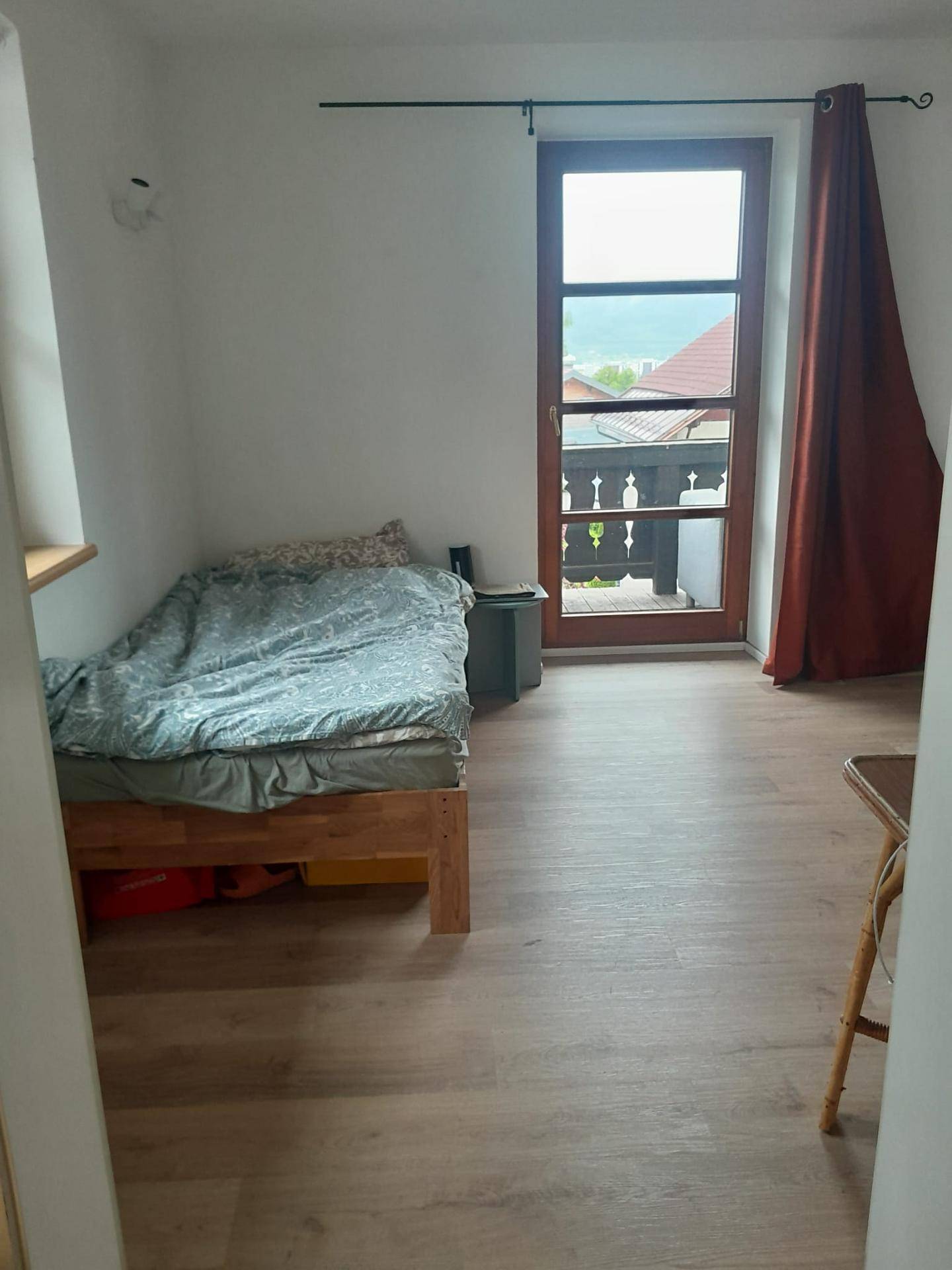 Schlafzimmer mit Einzelbett, Laminatboden und Zugang zu einem Balkon mit Ausblick.