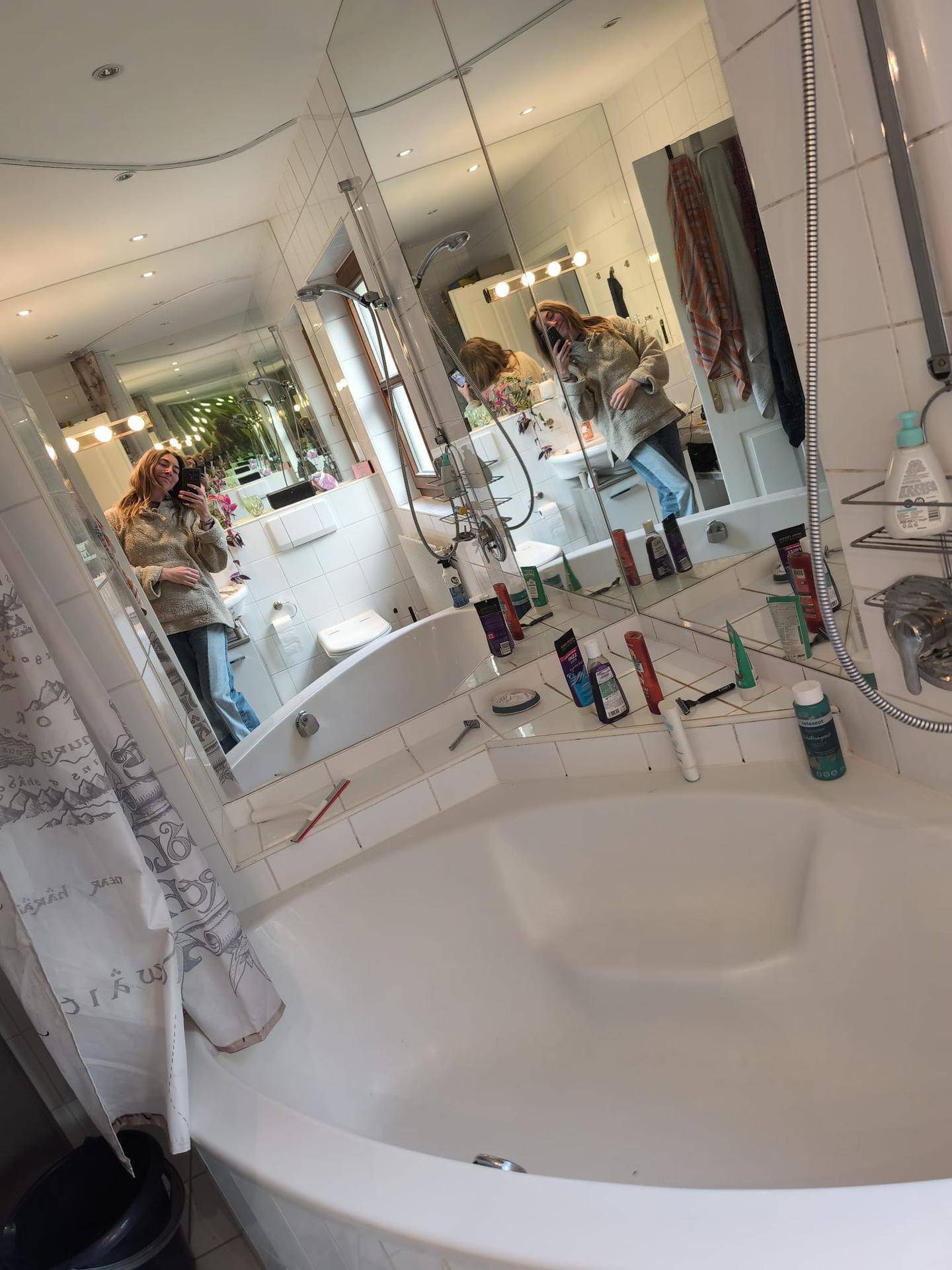 Badezimmer mit Eckbadewanne und vielen Spiegeln, die den Raum größer wirken lassen.