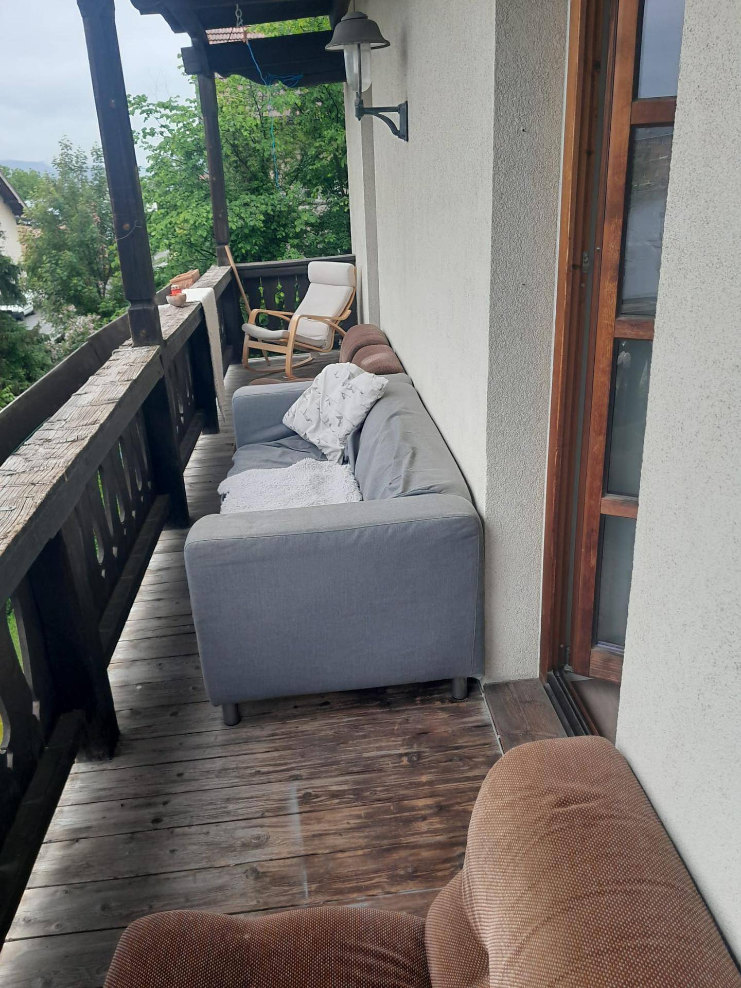 Holzbalkon mit bequemen Sitzmöbeln und Blick ins Grüne, ideal zum Entspannen.