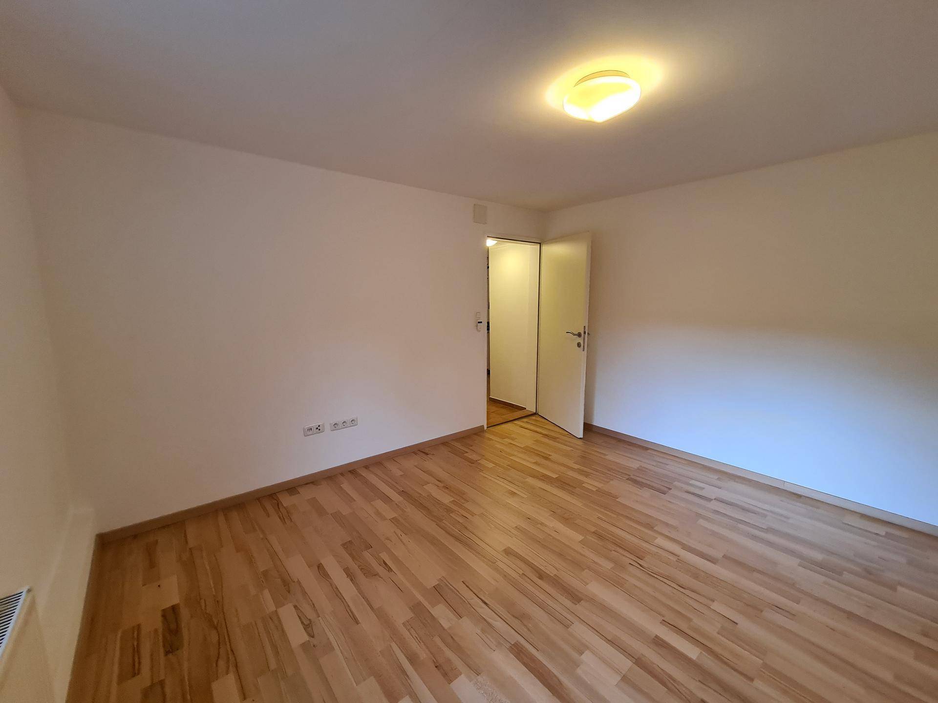 Geräumiges Schlafzimmer mit Holzboden und weiß gestrichenen Wänden, bereit zur Einrichtung.