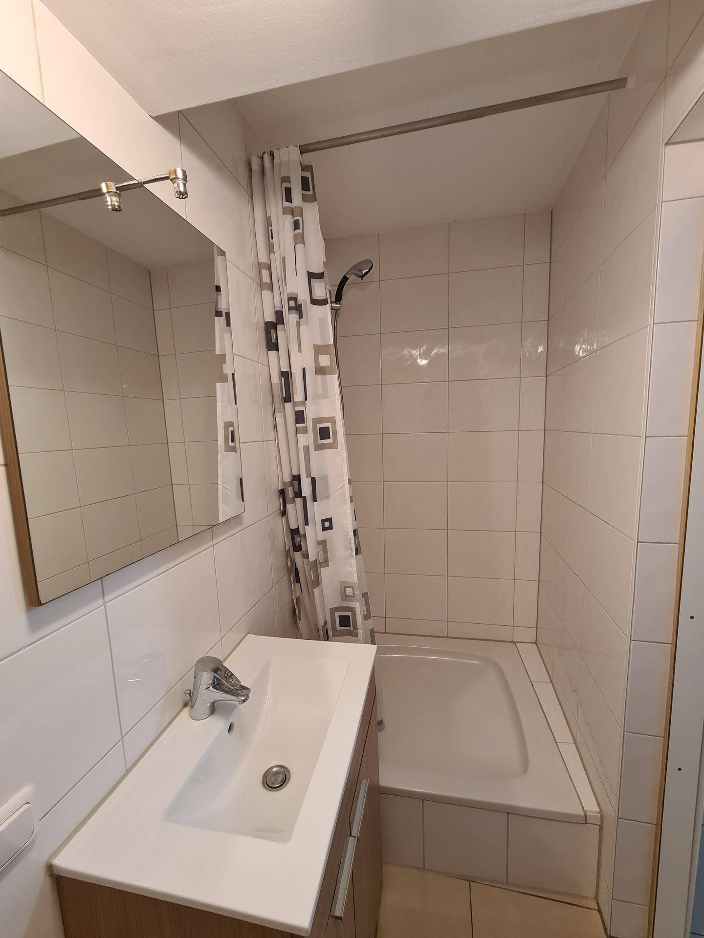 Badezimmer mit Badewanne, Duschvorhang, Waschbecken und weißen Fliesen.