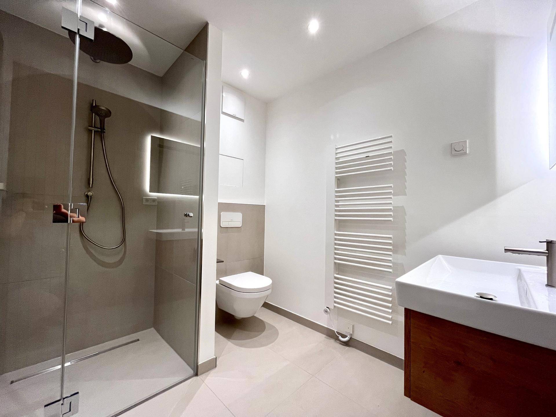 Modernes Badezimmer mit begehbarer Dusche, wandhängendem WC und elegantem Holzwaschtisch.