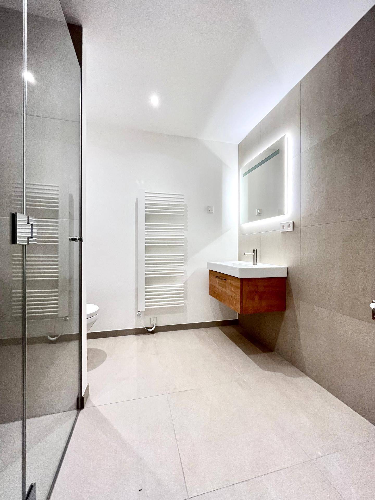 Modernes Badezimmer mit begehbarer Dusche, schwebendem Waschtisch und beheiztem Handtuchhalter.
