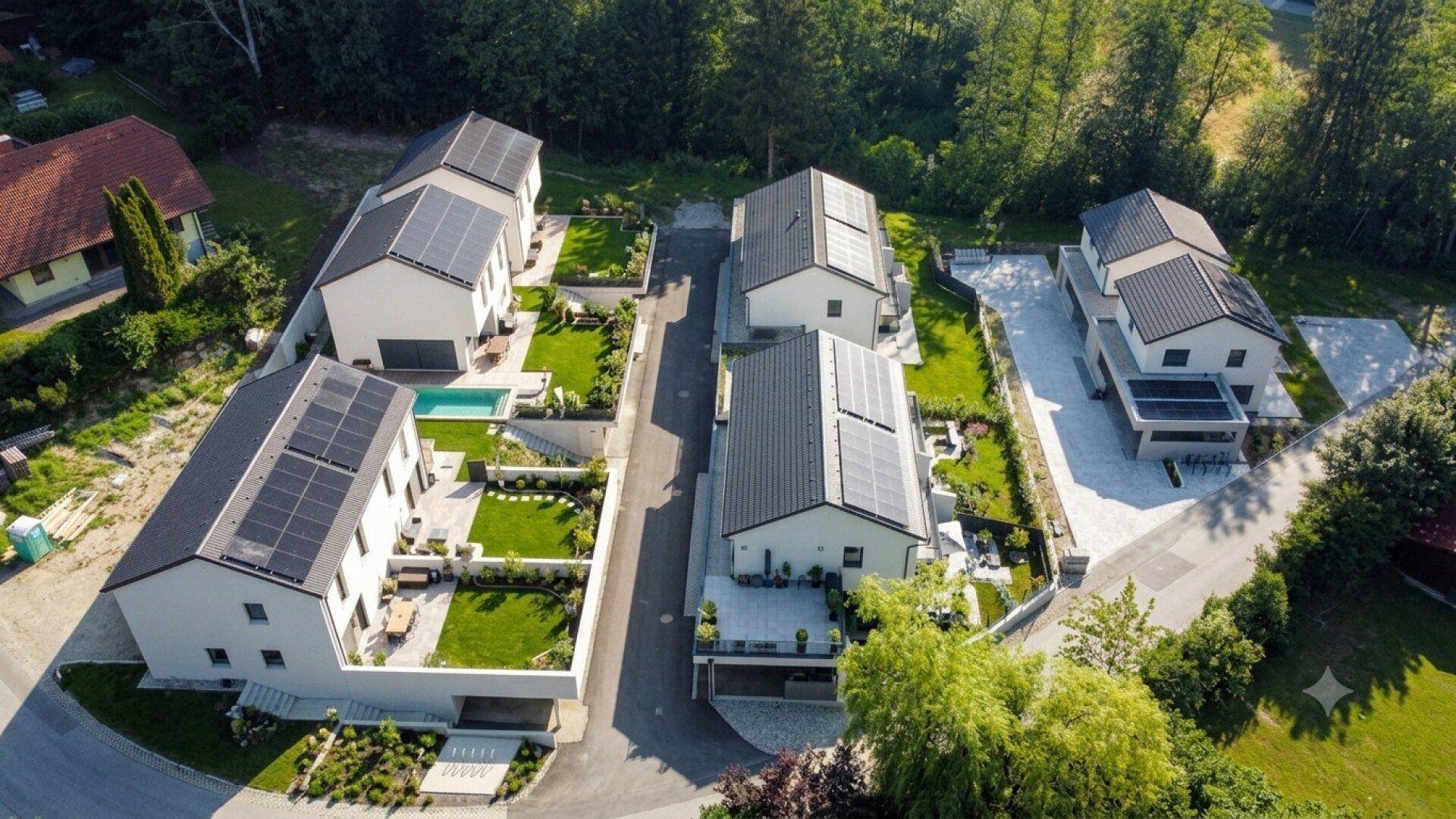 Vogelperspektive einer Siedlung mit modernen Häusern, Solaranlagen und gepflegten Gärten.