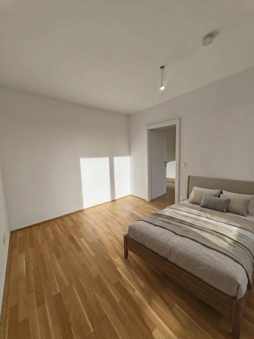Gemütliches Schlafzimmer mit Holzboden, weiß gestrichenen Wänden und natürlichem Lichteinfall.