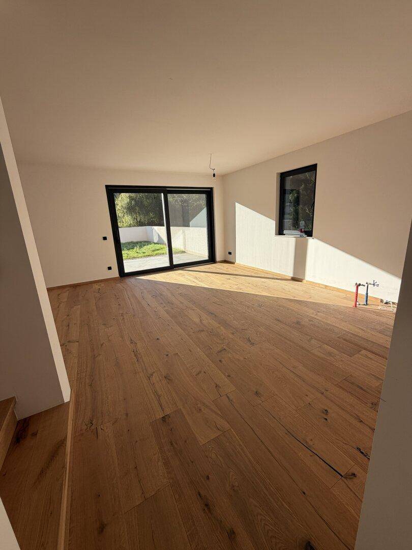 Geräumiges, helles Wohnzimmer mit Eichenparkettboden und großen Schiebetüren zur Terrasse.