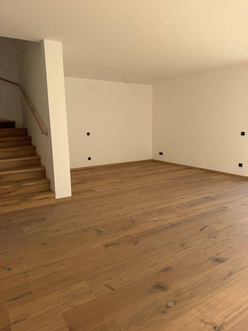 Geräumiger Wohnbereich mit Eichenparkettboden und offenem Zugang zur Holztreppe.