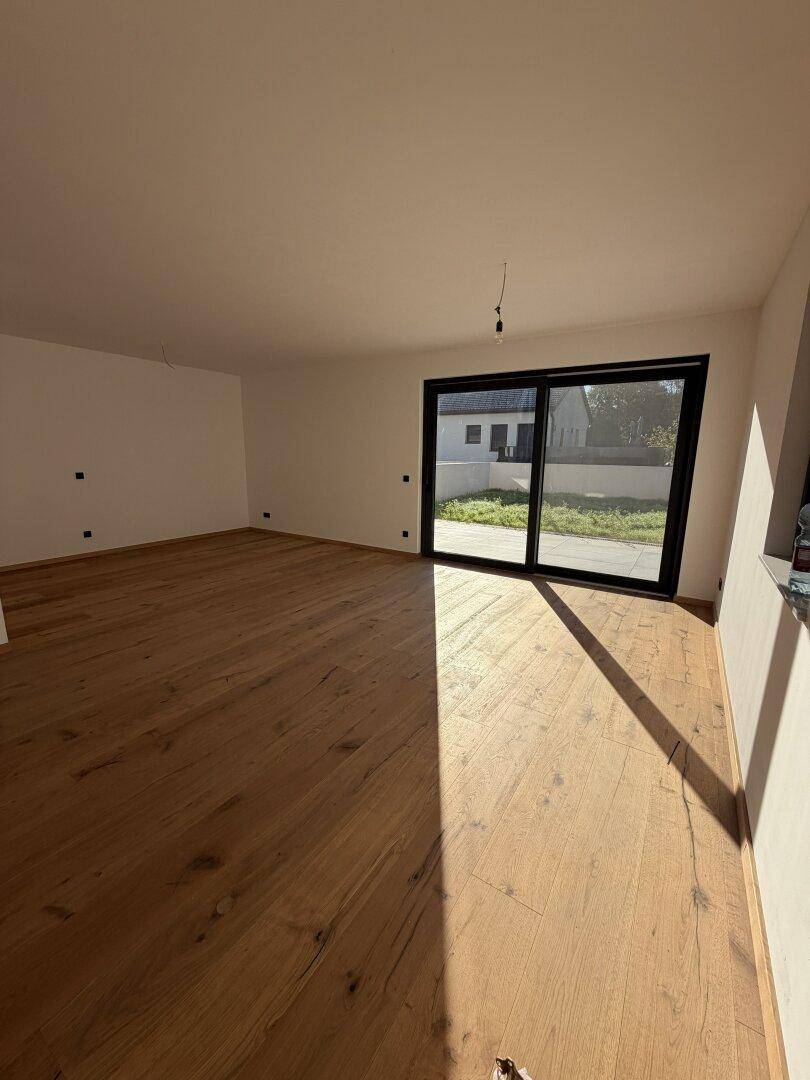 Geräumiger Wohnraum mit Eichenparkettboden und großer Schiebetür, die viel Tageslicht hereinlässt.