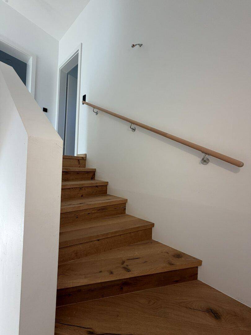 Moderne Holztreppe mit Eichenstufen und minimalistischem Holzgeländer, das zu den oberen Etagen führt.