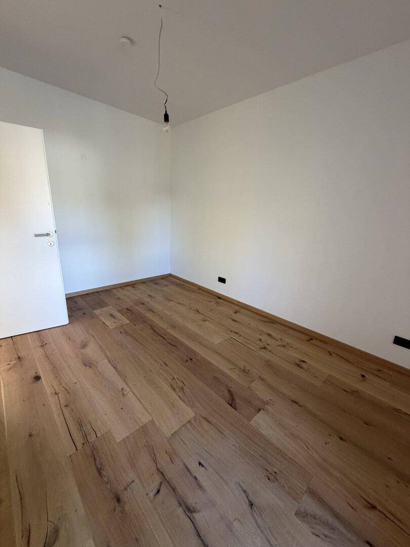 Geräumiges Schlafzimmer mit Eichenparkettboden und weißen Wänden, bereit zur individuellen Gestaltung.