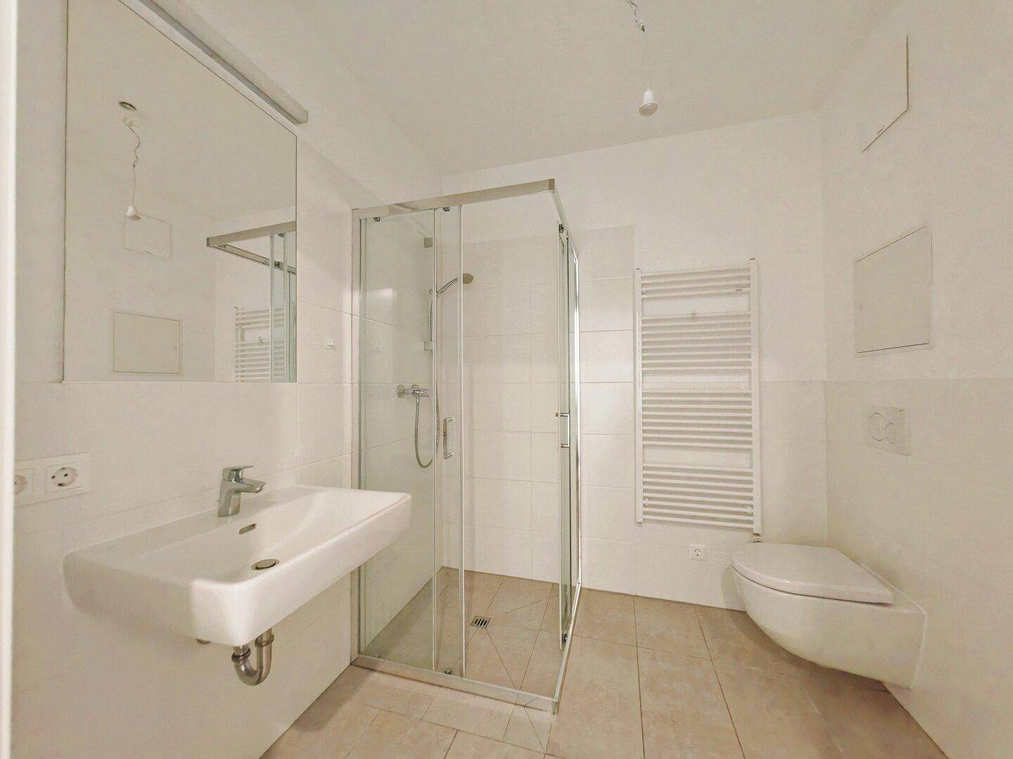 Modernes Badezimmer mit Duschkabine, wandhängendem WC und beheiztem Handtuchhalter.