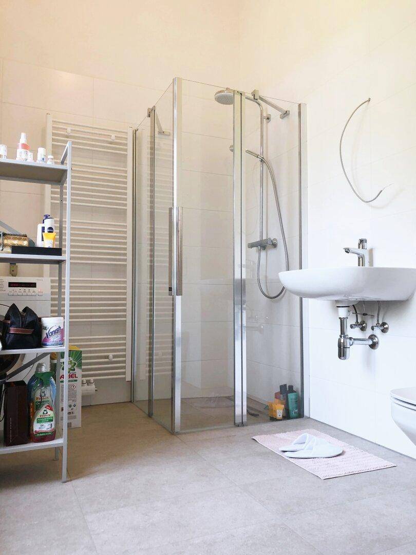 Modernes Badezimmer mit Duschkabine, Waschbecken und beheiztem Handtuchhalter.