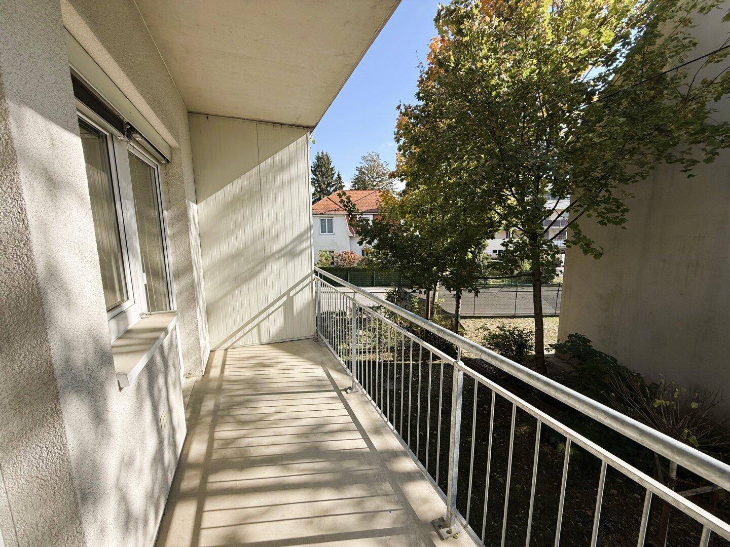 Heller Balkon mit Metallgeländer und Blick auf die grüne Umgebung.