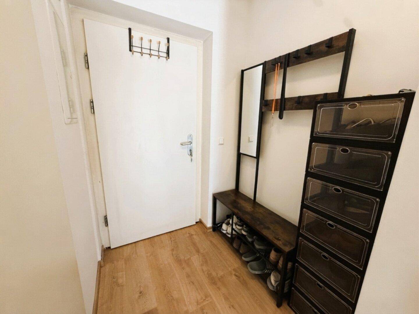 Eingangsbereich mit Garderobe, Schuhregal und Spiegel, ausgestattet mit Laminatboden.