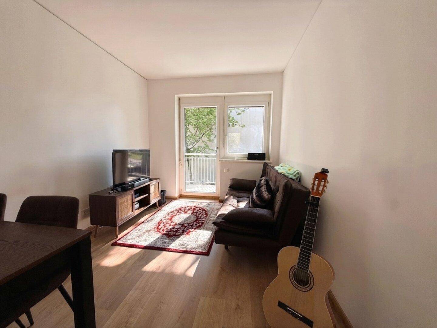 Gemütliches Wohnzimmer mit Sofa, Fernseher und hellem Laminatboden.
