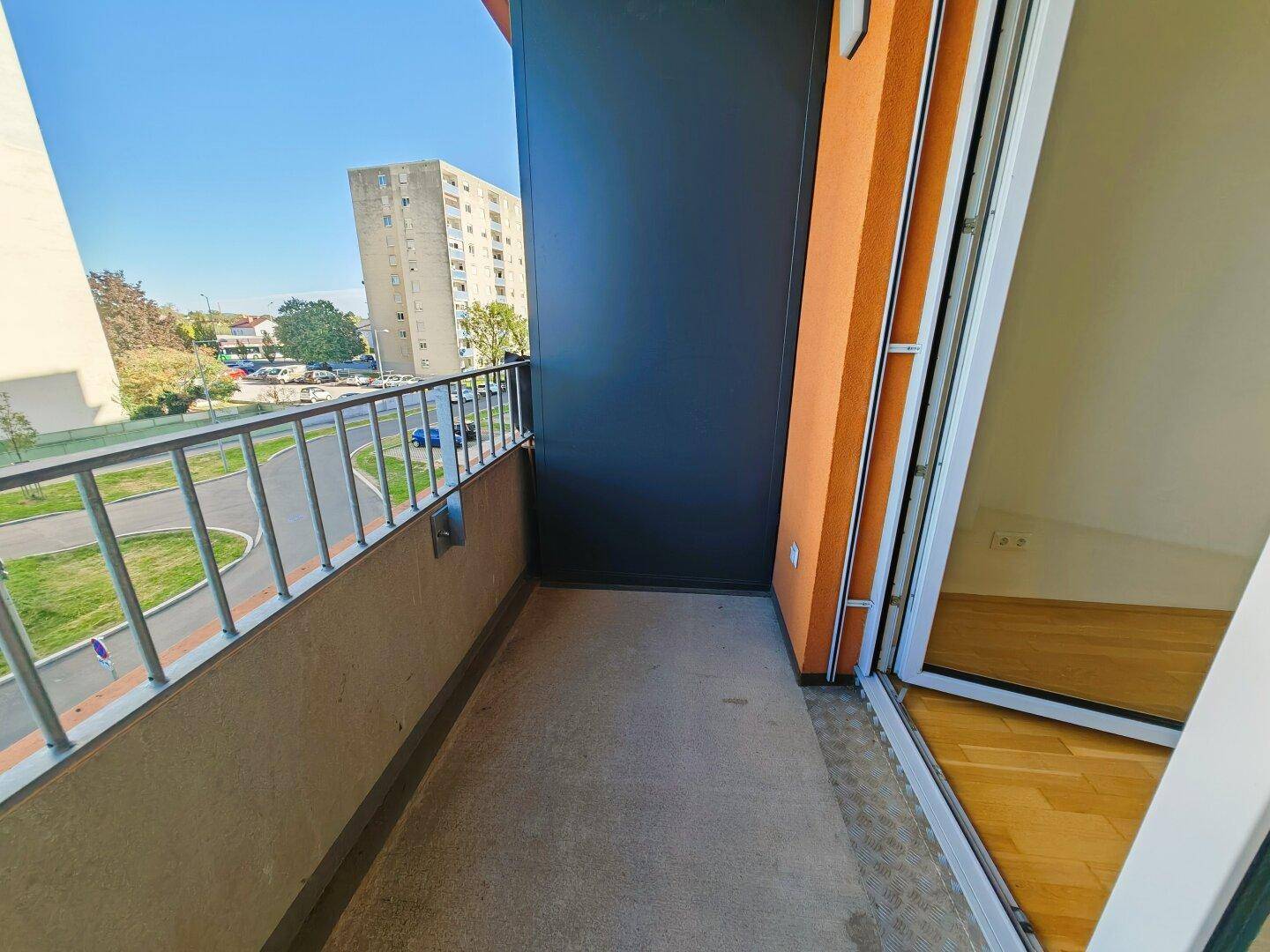 Balkon mit Metallgeländer und Blick auf die umliegende Wohnbebauung und Grünflächen.