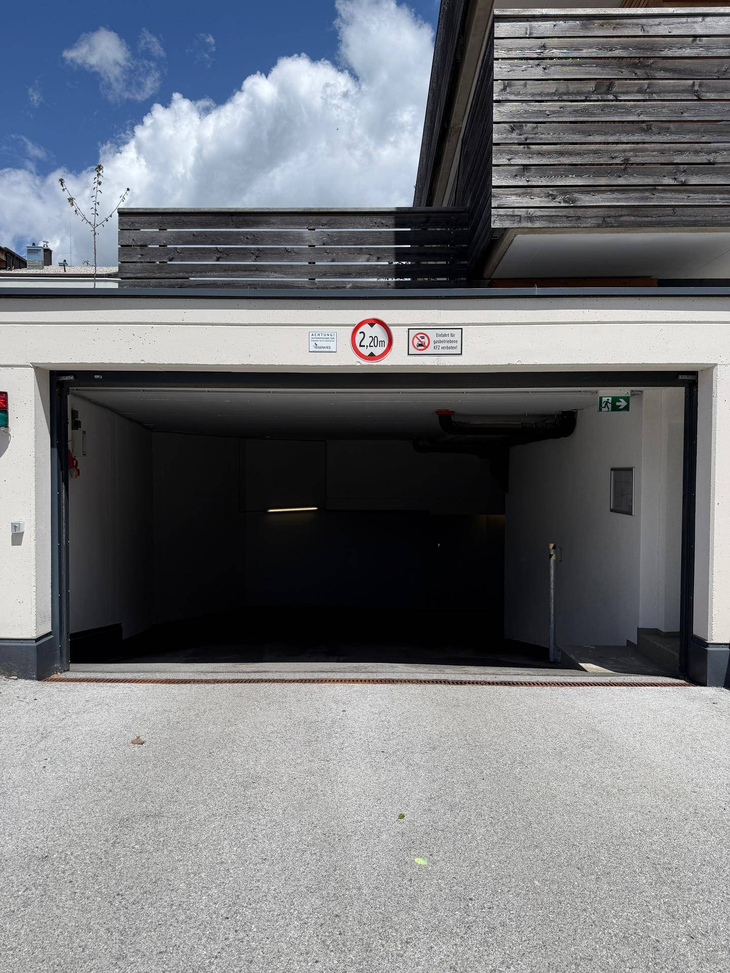 Offenes Garagentor einer Tiefgarage mit Blick in den dunklen Innenraum.
