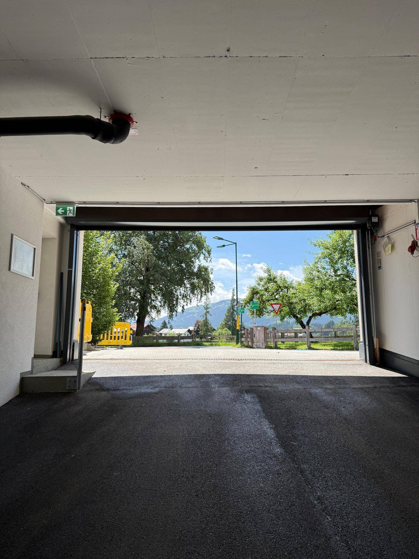Innenansicht der Tiefgarage mit offenem Gittertor und weitem Blick auf die Landschaft.