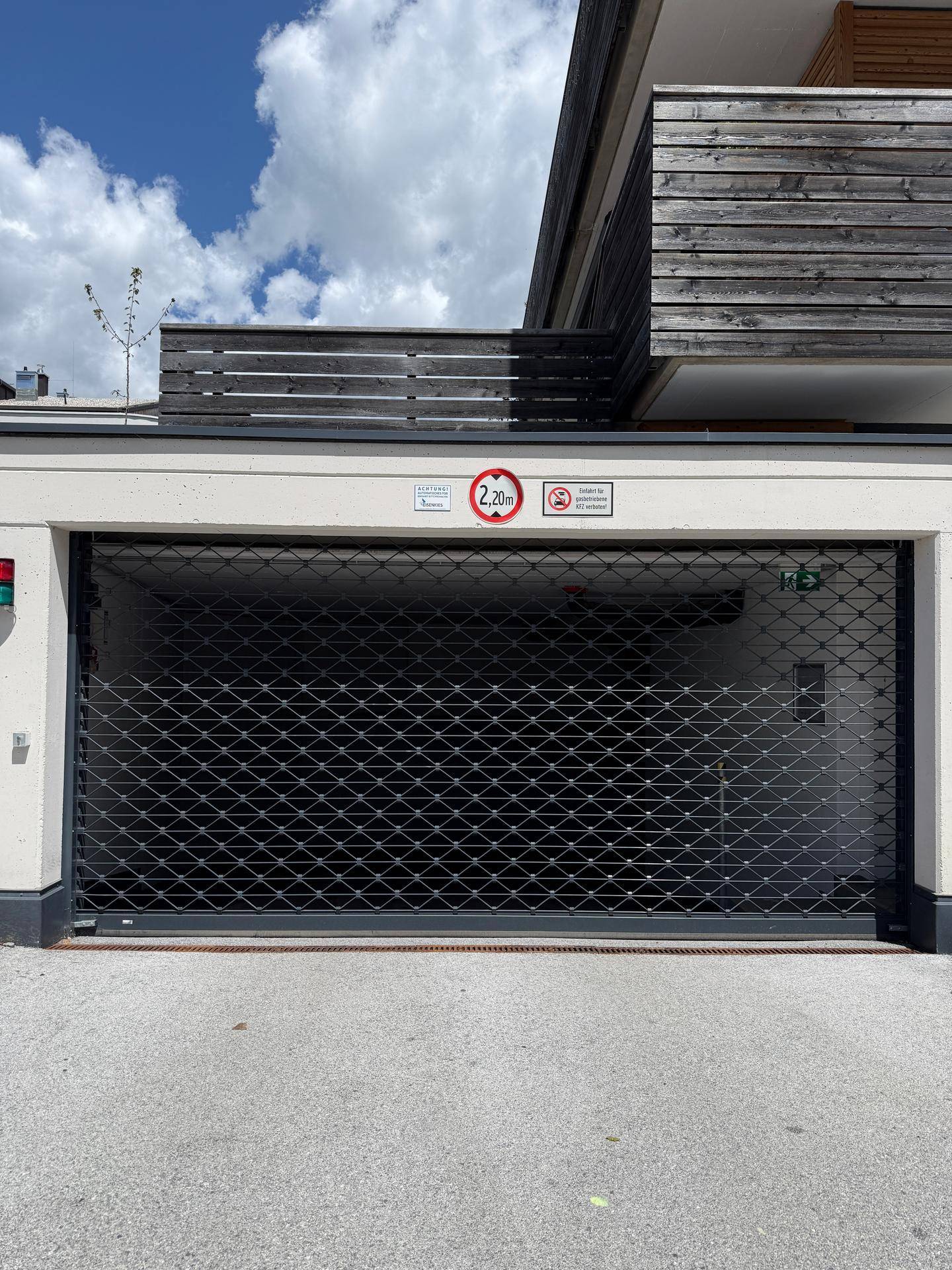 Geschlossenes Garagentor einer Tiefgarage mit Höhenbegrenzungsschild.