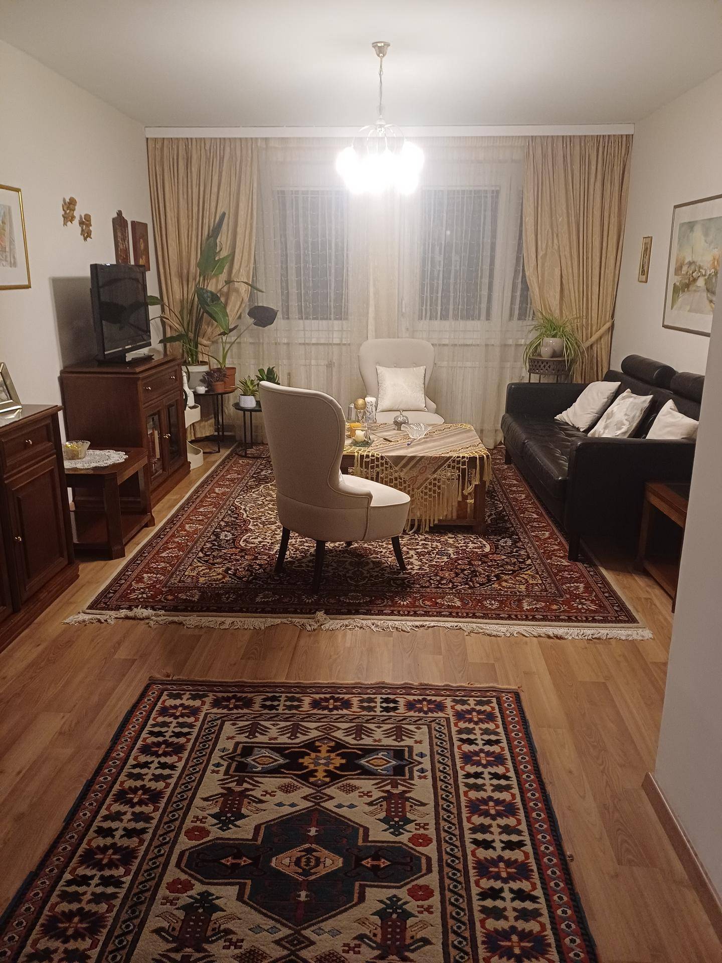 Klassisches Wohnzimmer mit bequemen Sitzmöbeln, gemusterten Teppichen und Holzboden.