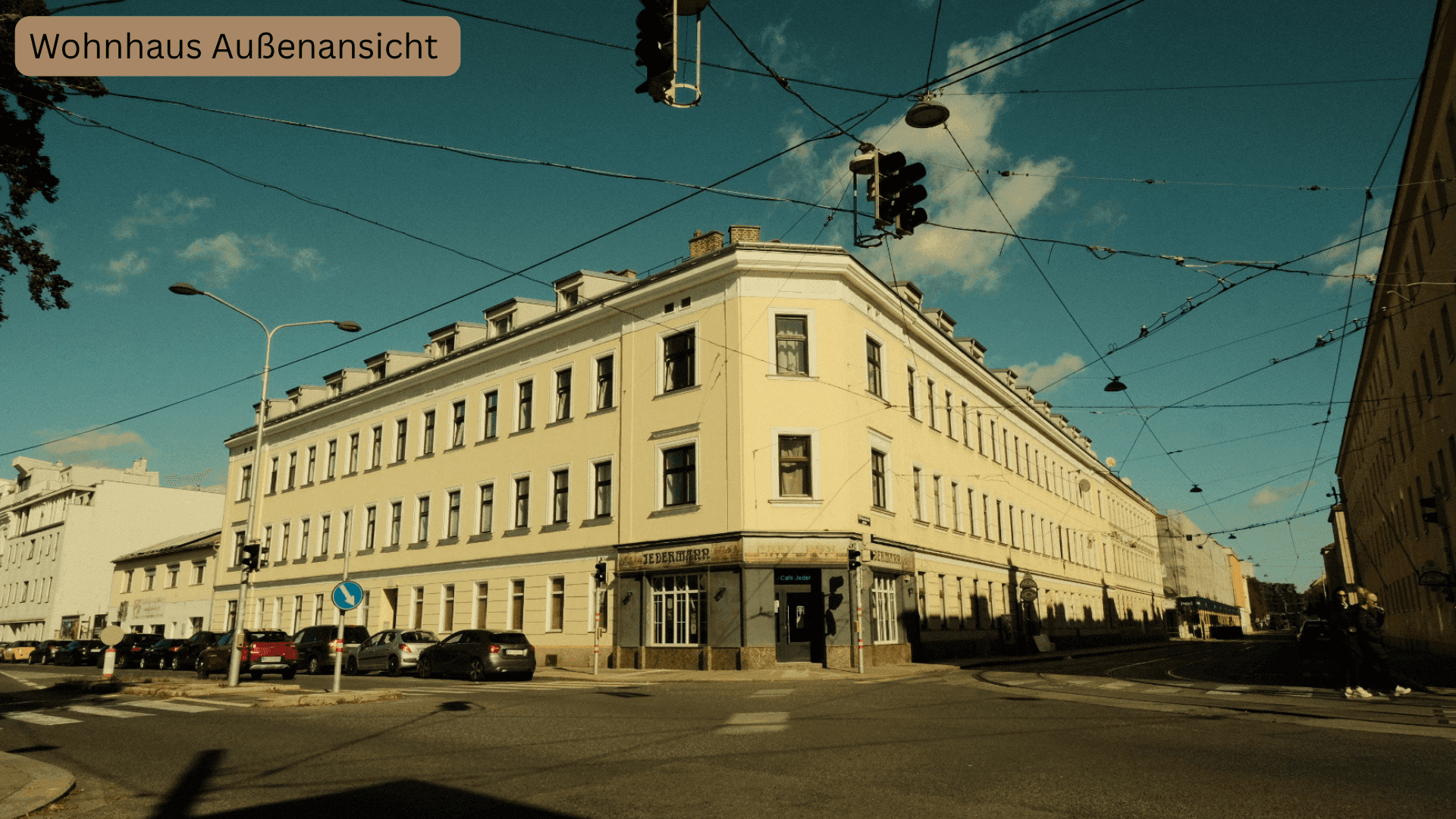 Historisches Eckgebäude in städtischer Umgebung mit vielen Fenstern und belebter Straße.