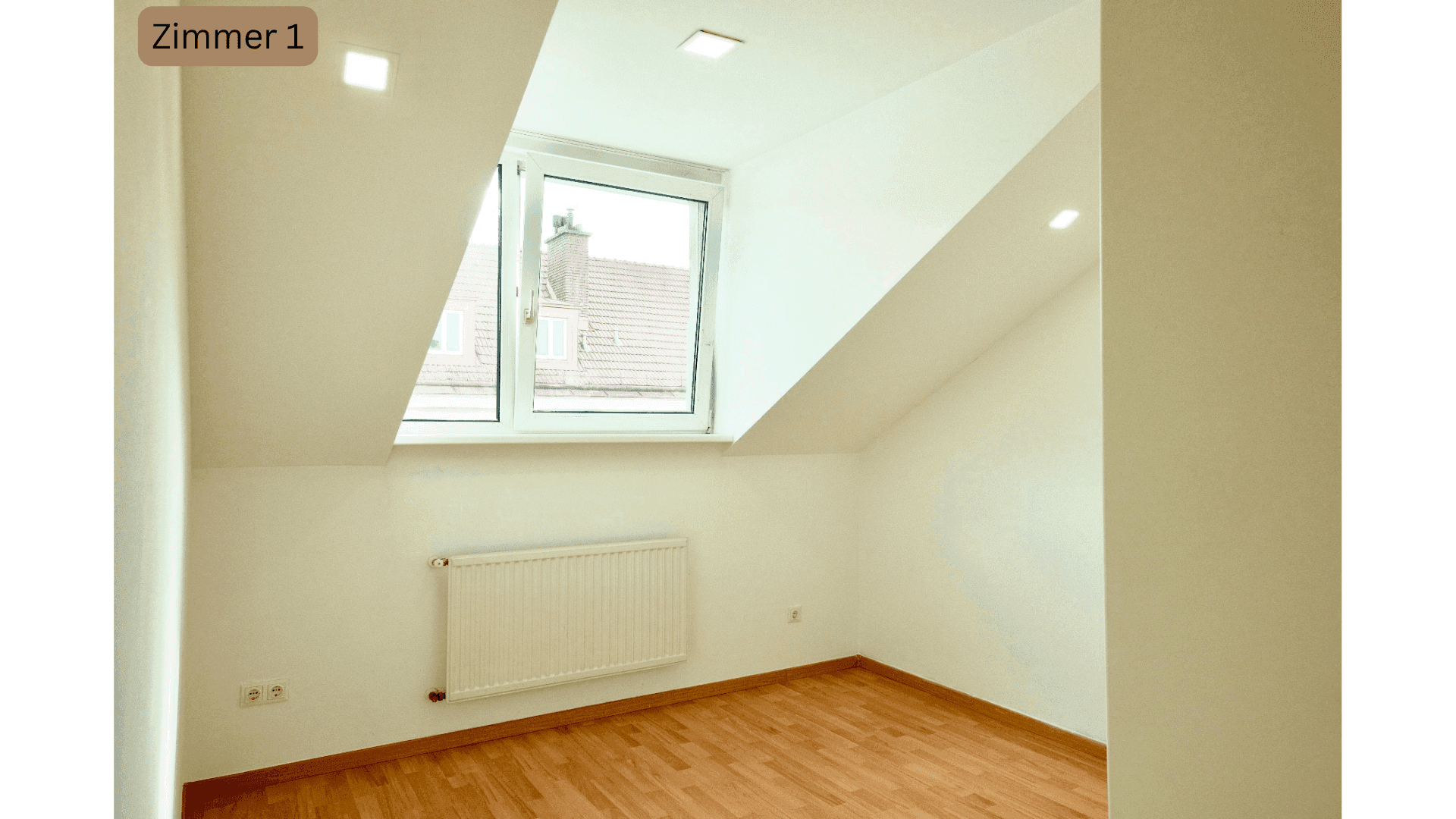 Leeres Schlafzimmer im Dachgeschoss mit Fenster, Heizkörper und Holzboden.