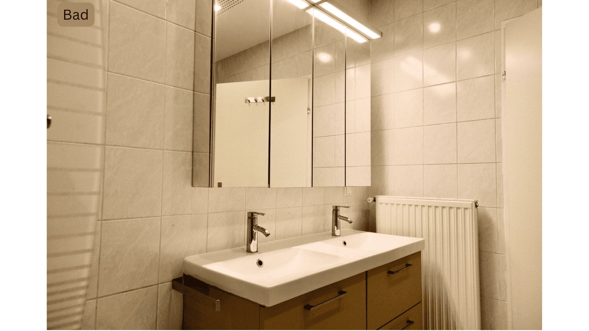 Badezimmer mit Doppelwaschbecken, großem Spiegelschrank und Fliesenwänden.