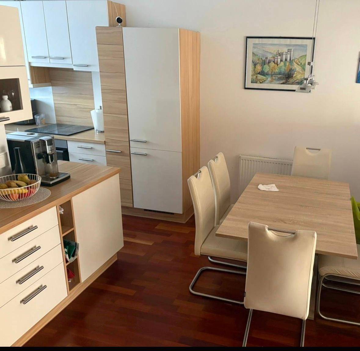 Essbereich in der Küche mit Holztisch, Stühlen und Blick auf die Einbauküche.