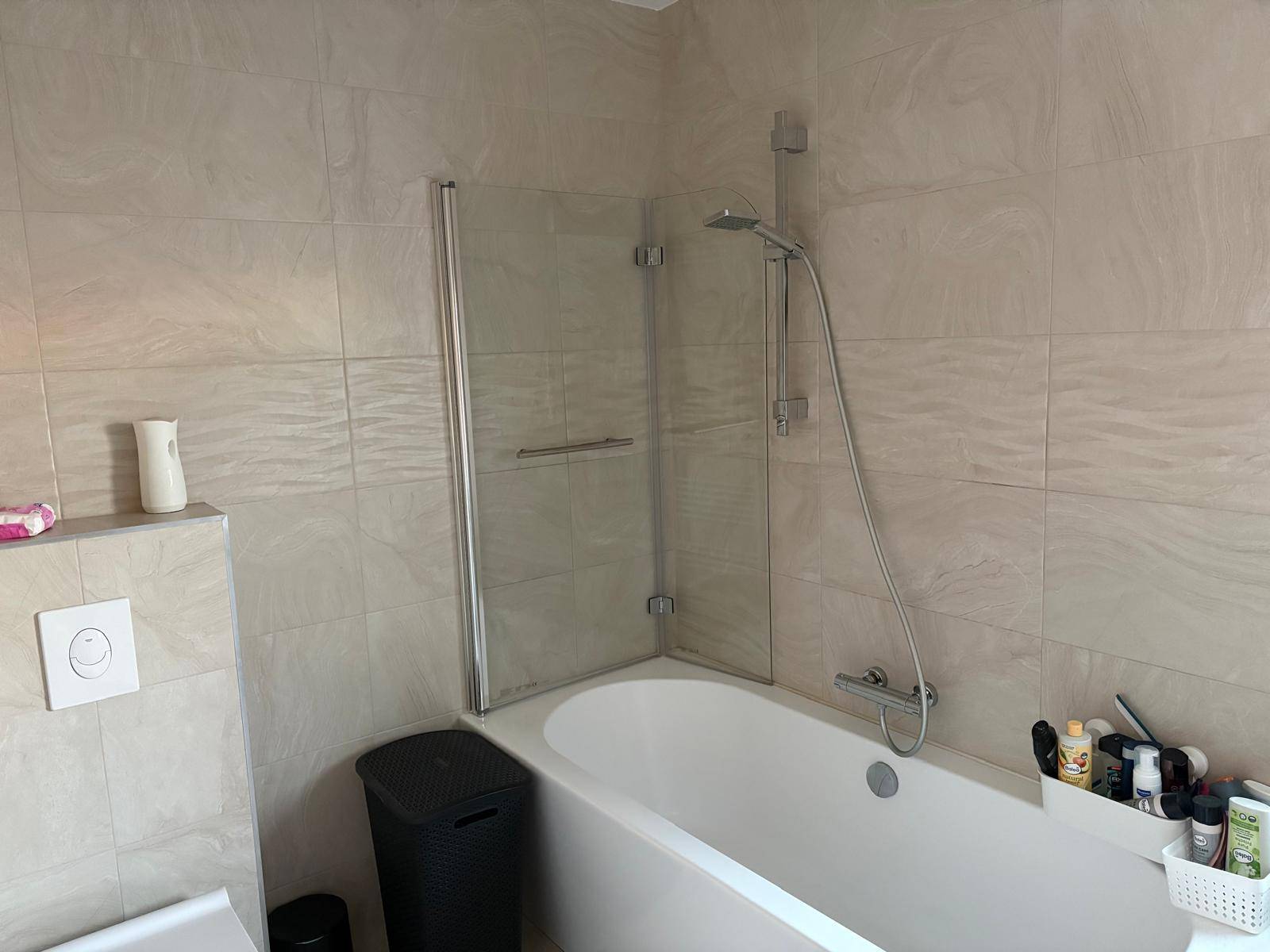 Badezimmer mit Badewanne, Duschabtrennung und hellen Wandfliesen.