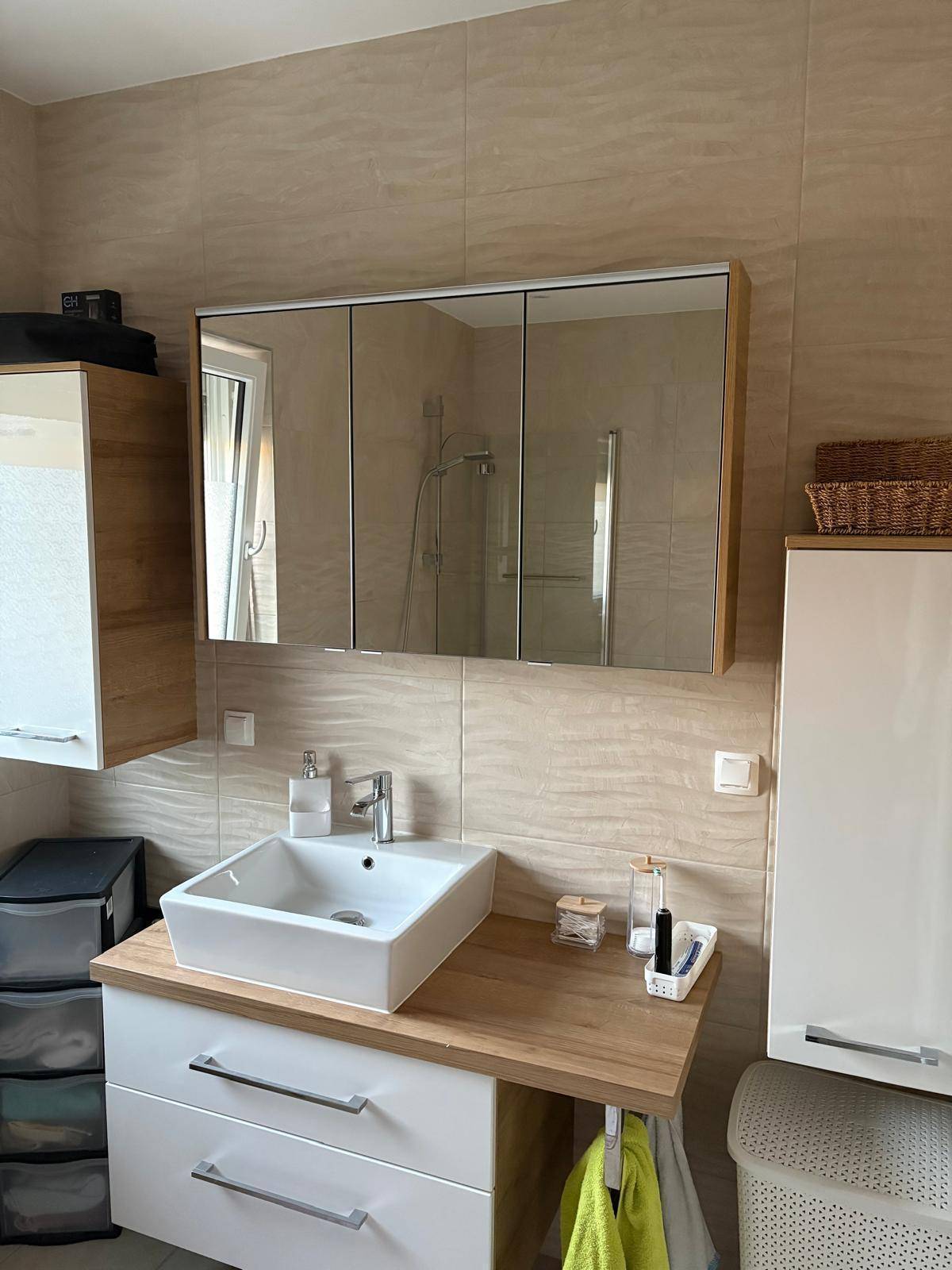 Modernes Badezimmer mit Waschbecken, Spiegelschrank und hellen Fliesen.