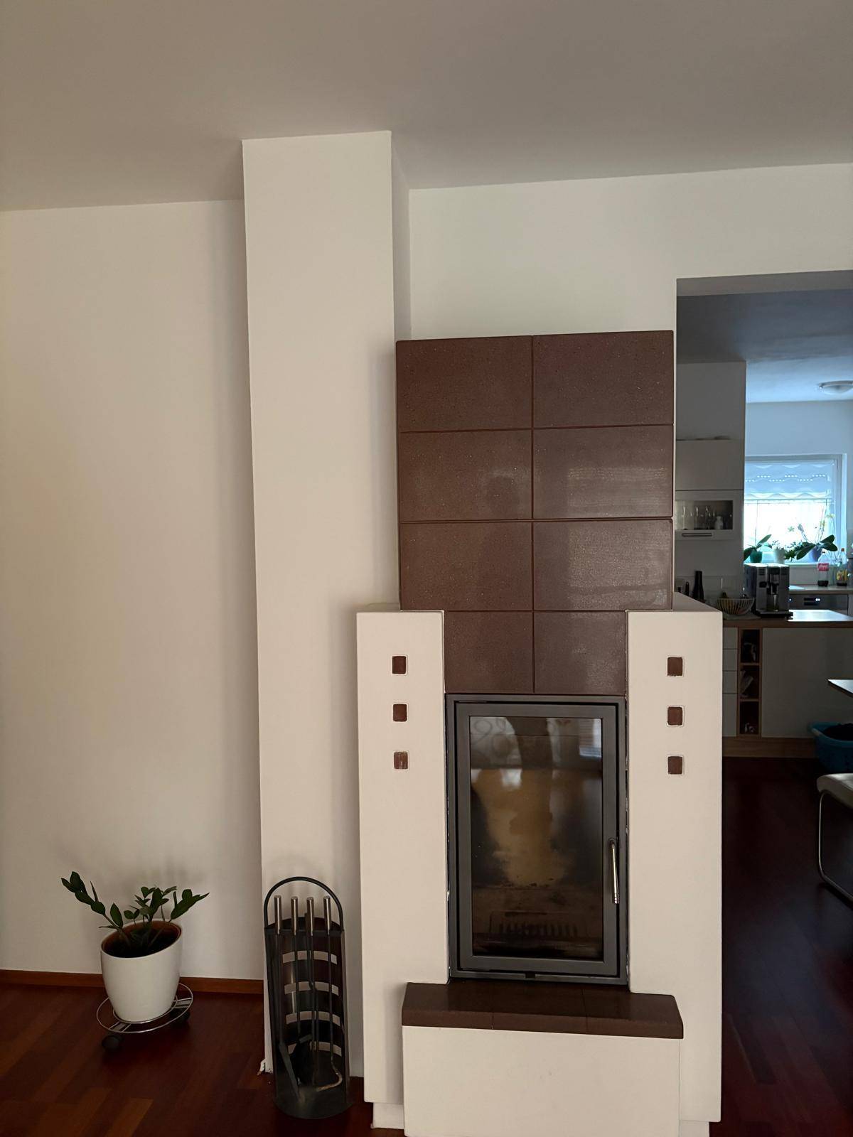 Moderner Kamin im Wohnzimmer mit braunen Fliesenakzenten und Holzfußboden.