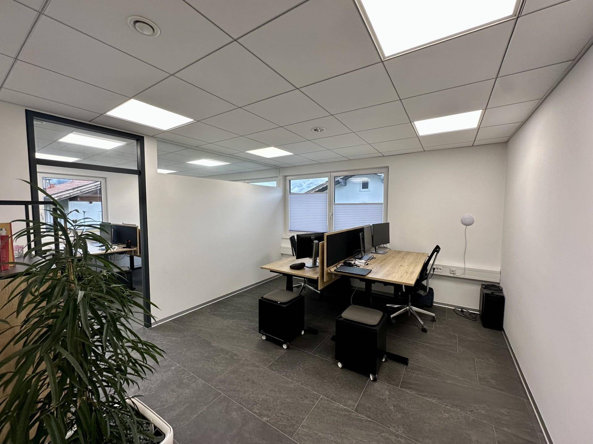 Geräumiges Büro mit mehreren Arbeitsplätzen, modernen Möbeln und Blick auf die Umgebung.