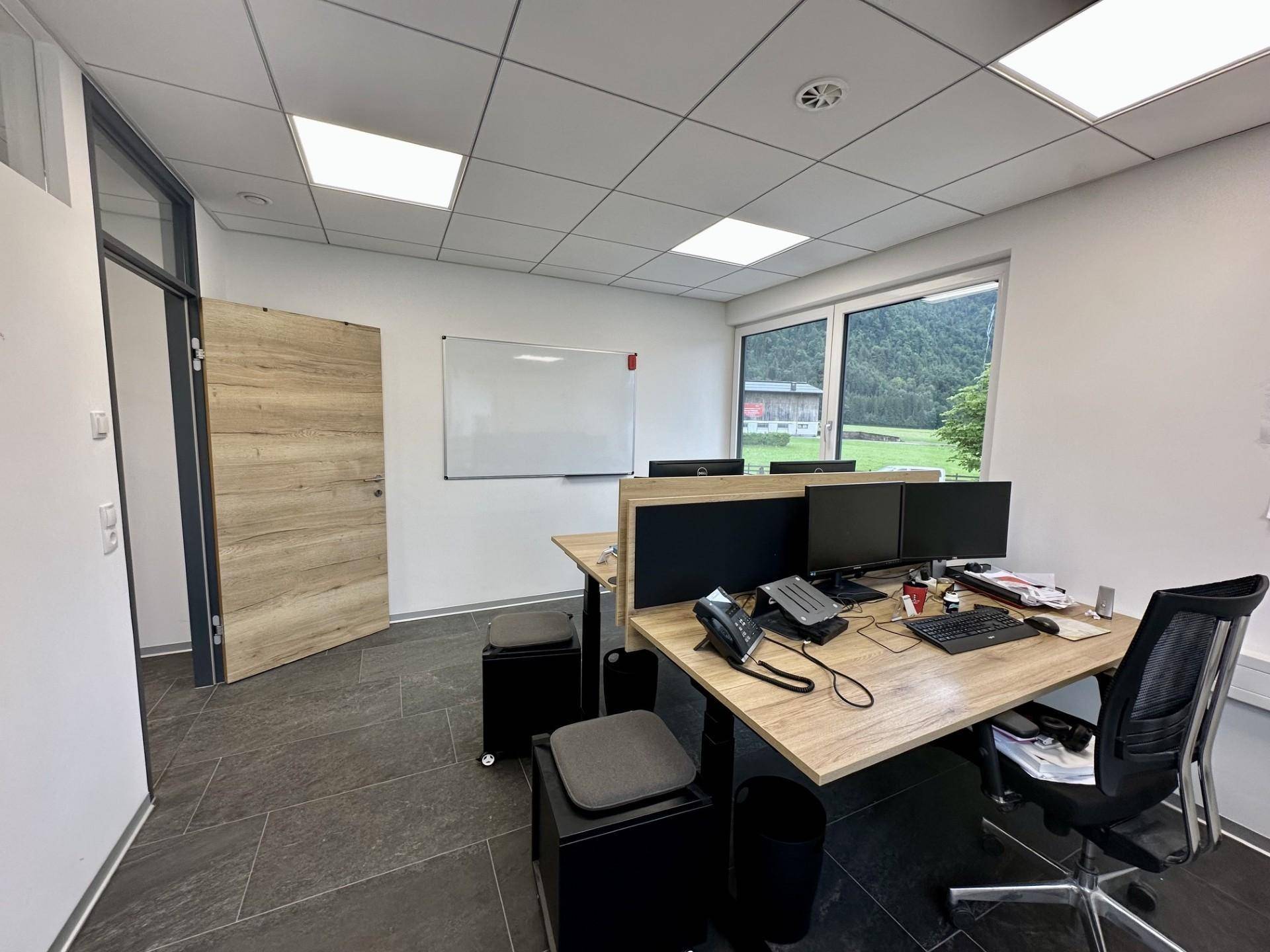 Helles Büro mit zwei Arbeitsplätzen, Holztür und weitem Blick auf die grüne Landschaft.