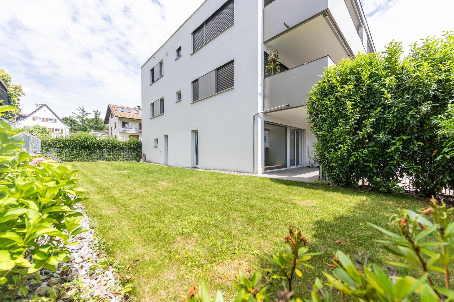 Gepflegter Gartenbereich mit Rasenfläche und Blick auf die moderne Gebäudefassade.