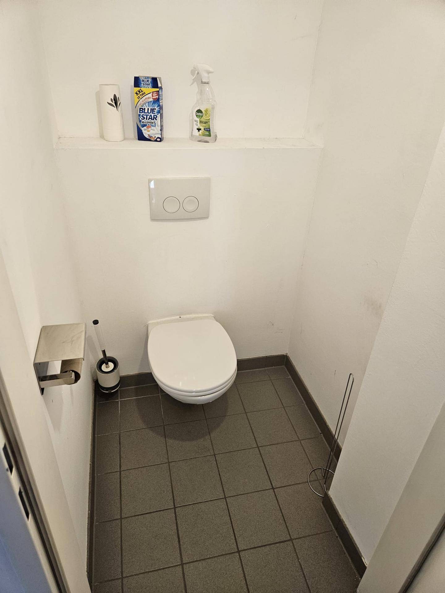 Kleines Gäste-WC mit Wand-WC und Fliesenboden.