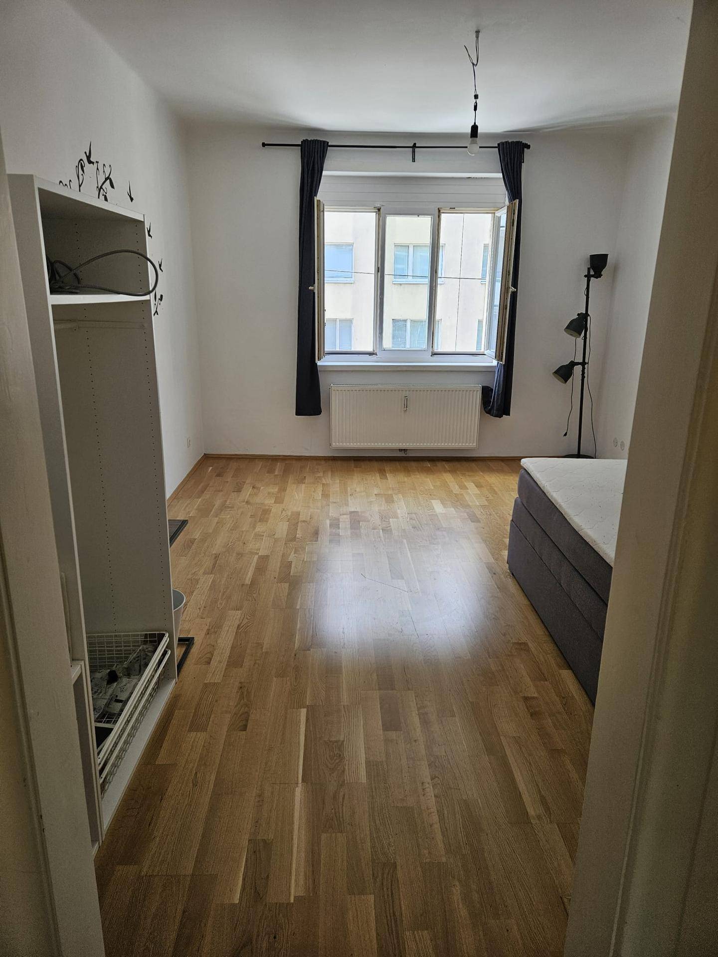 Helles Schlafzimmer mit Holzboden und Fenster mit Blick auf die Umgebung.