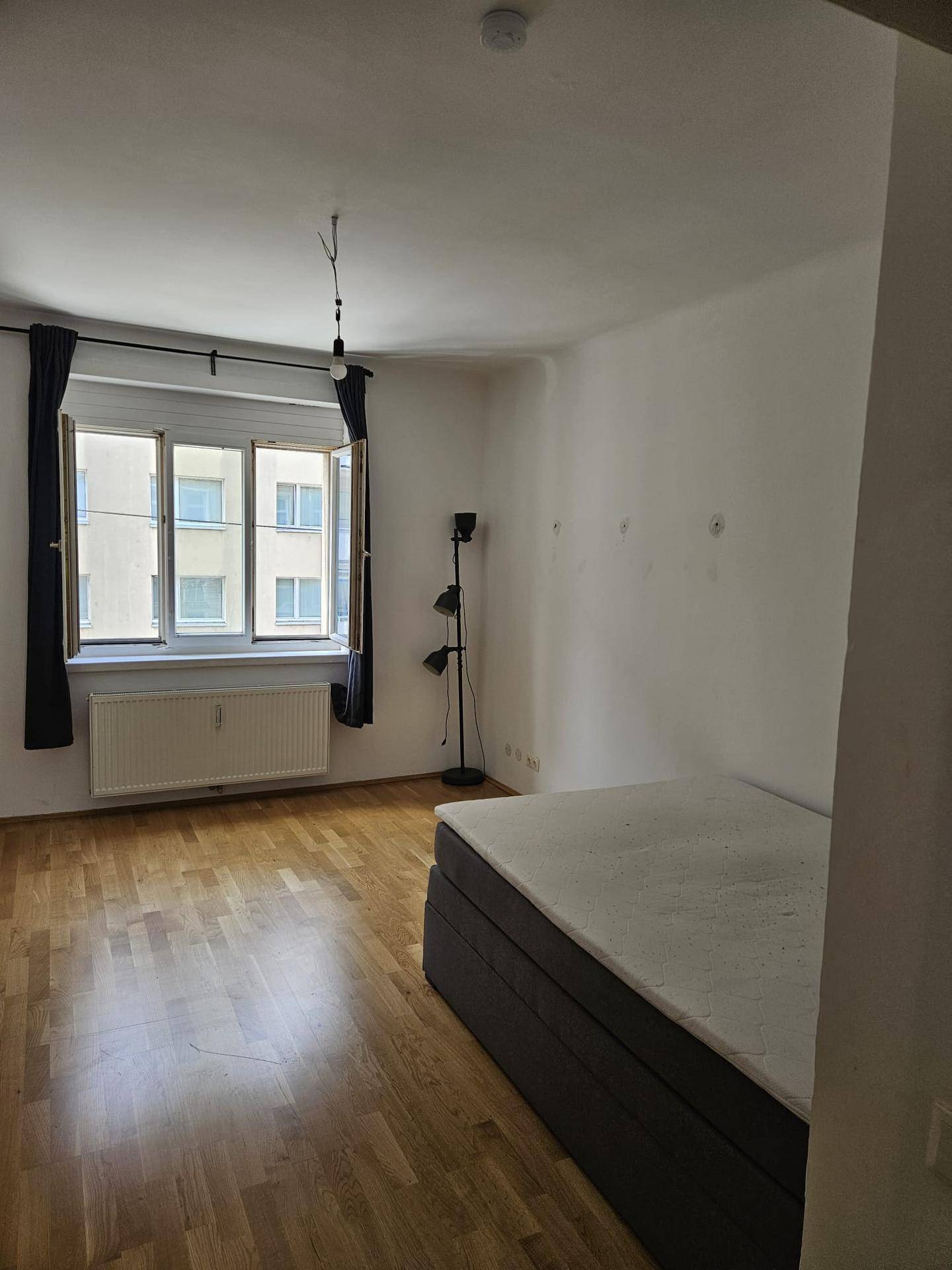 Geräumiges Schlafzimmer mit Holzboden und großem Fenster, das viel Licht hereinlässt.