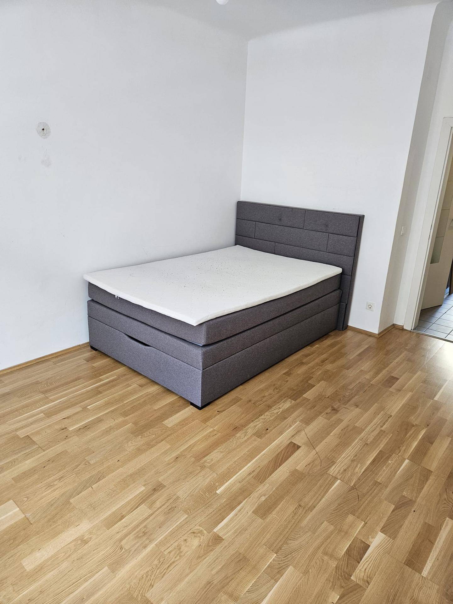 Schlafzimmer mit Holzboden und einem modernen Boxspringbett.