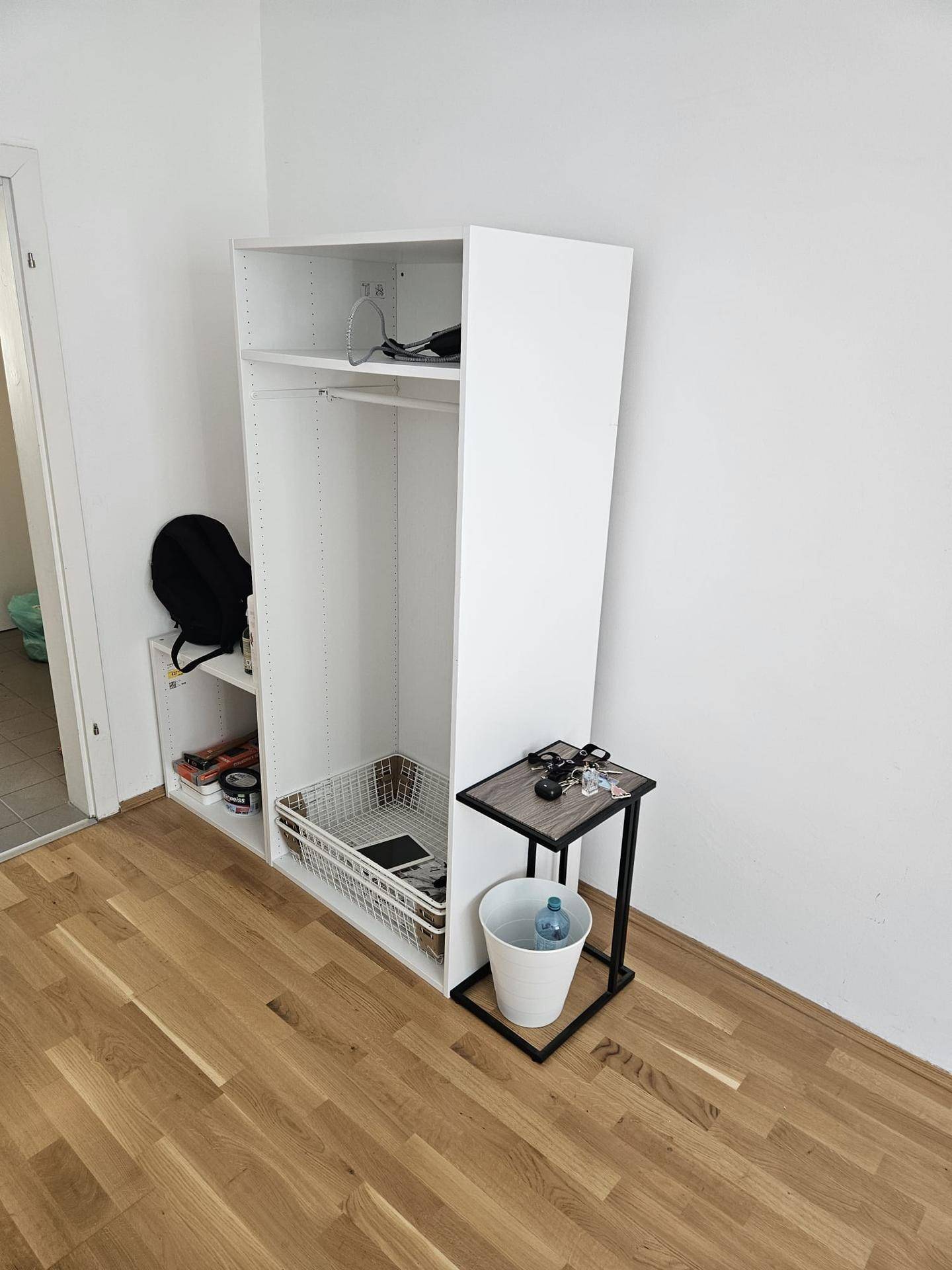 Schlafzimmer mit Holzboden und offenem Kleiderschrank, praktisch und funktional.