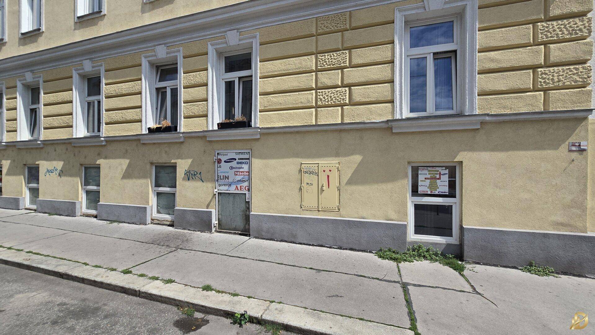 Weitläufige Ansicht der Gebäudefassade von der Straße aus mit vielen Fenstern und dekorativen Elementen.