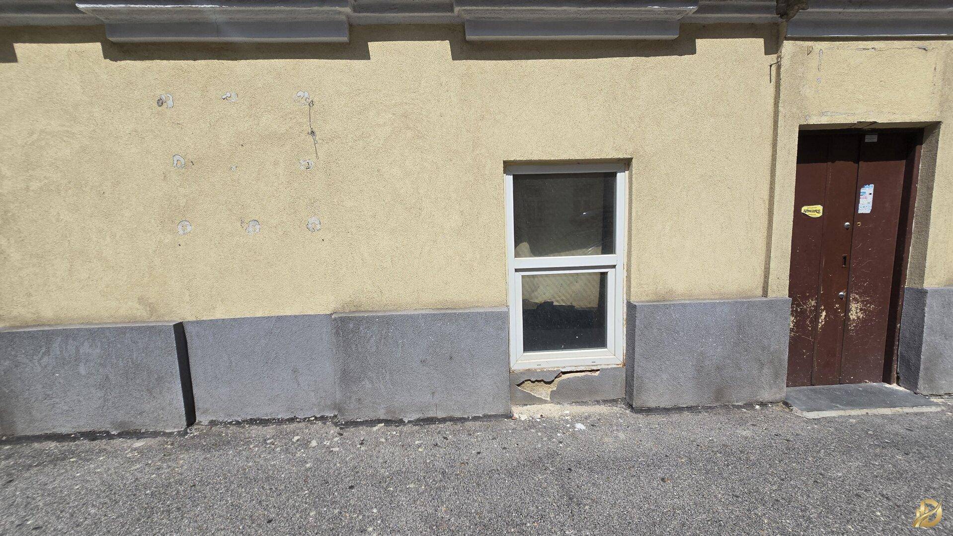 Fassade eines Gebäudes im Erdgeschoss mit einem Fenster und einer Eingangstür.