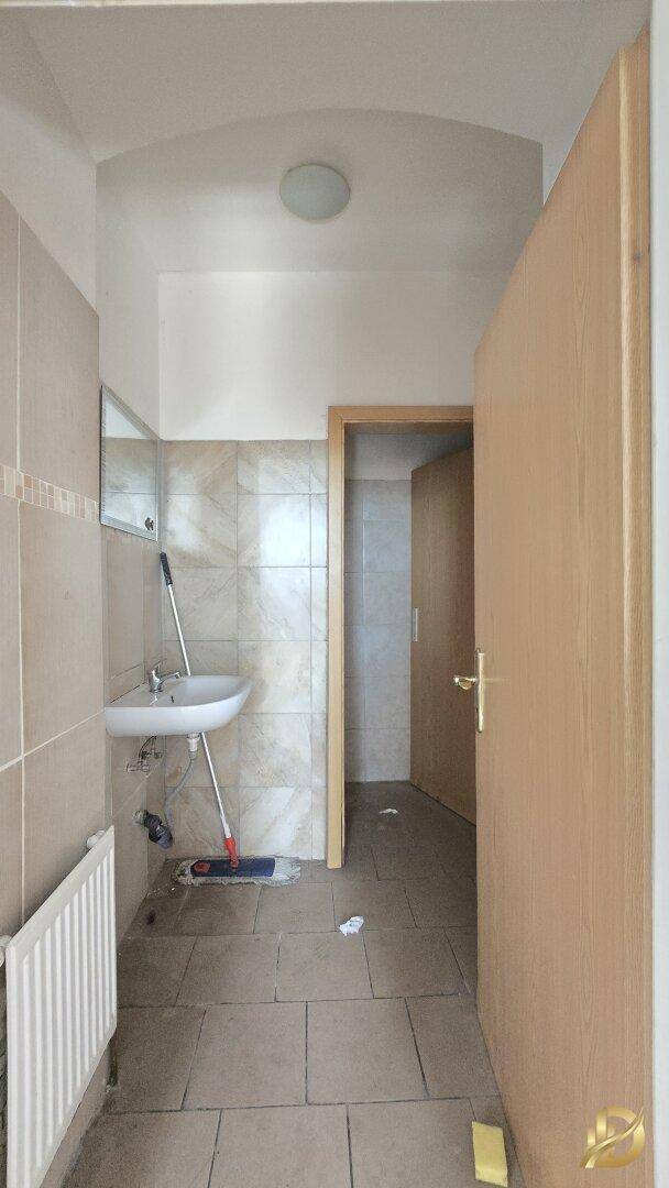 Geräumigeres Gäste-WC mit Waschbecken, Heizkörper und einem Spiegel an der Wand.