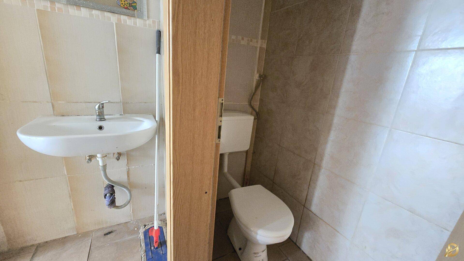 Kleines Badezimmer oder Gäste-WC mit Waschbecken und Toilette, komplett gefliest.