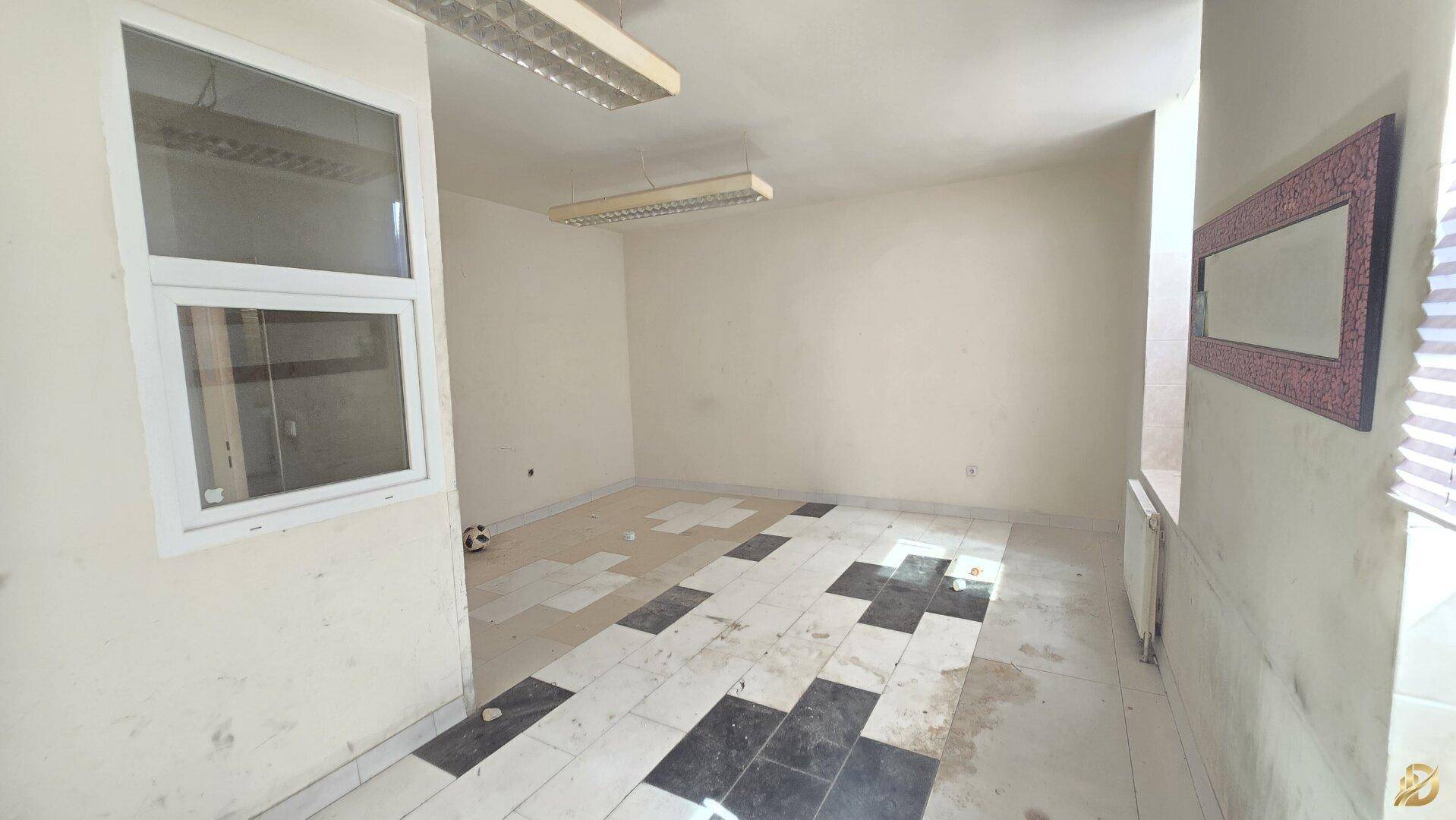 Raum mit schwarz-weiß gefliestem Boden, einem Fenster und Deckenleuchten, geeignet als Büro.