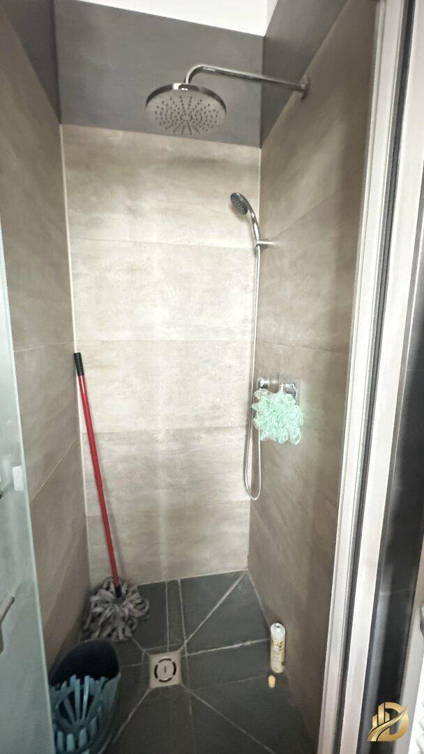 Duschkabine mit Regendusche und Handbrause, ausgestattet mit modernen grauen Fliesen.